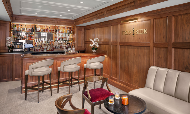 A sophisticated wood-paneled bar area with leather stools and comfortable lounge seating in Portland Maine.