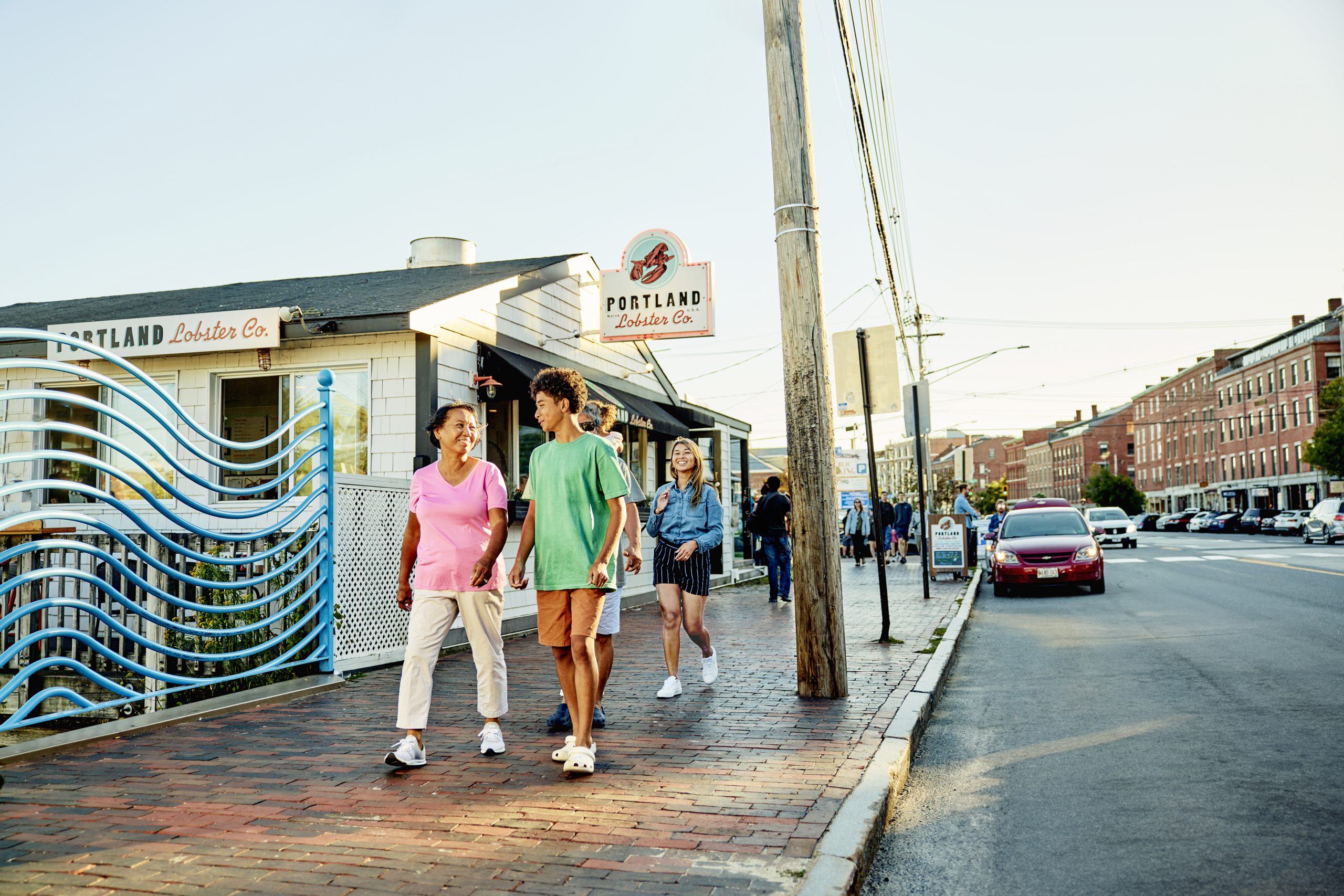 A group of people walking on a brick sidewalk in Downtown Portland, Maine.