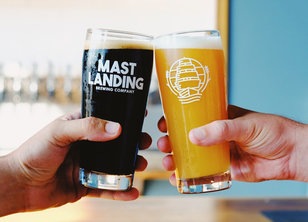 Two hands holding glasses of dark and light beer in a toast in Portland Maine. Photo credit: Visit Freeport