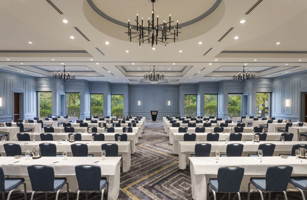 A large conference room with rows of tables and chairs facing a podium in Portland Maine.