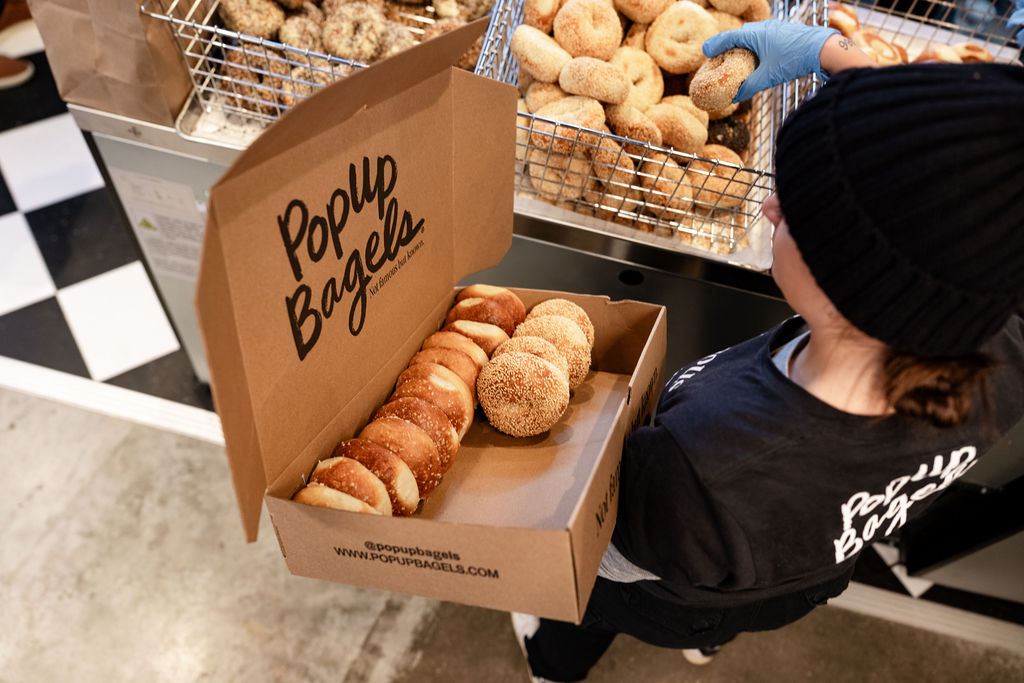 A person holding a box of fresh PopUp Bagels in Portland, Maine. Photo Credit: Shado Of A Rose Photography
