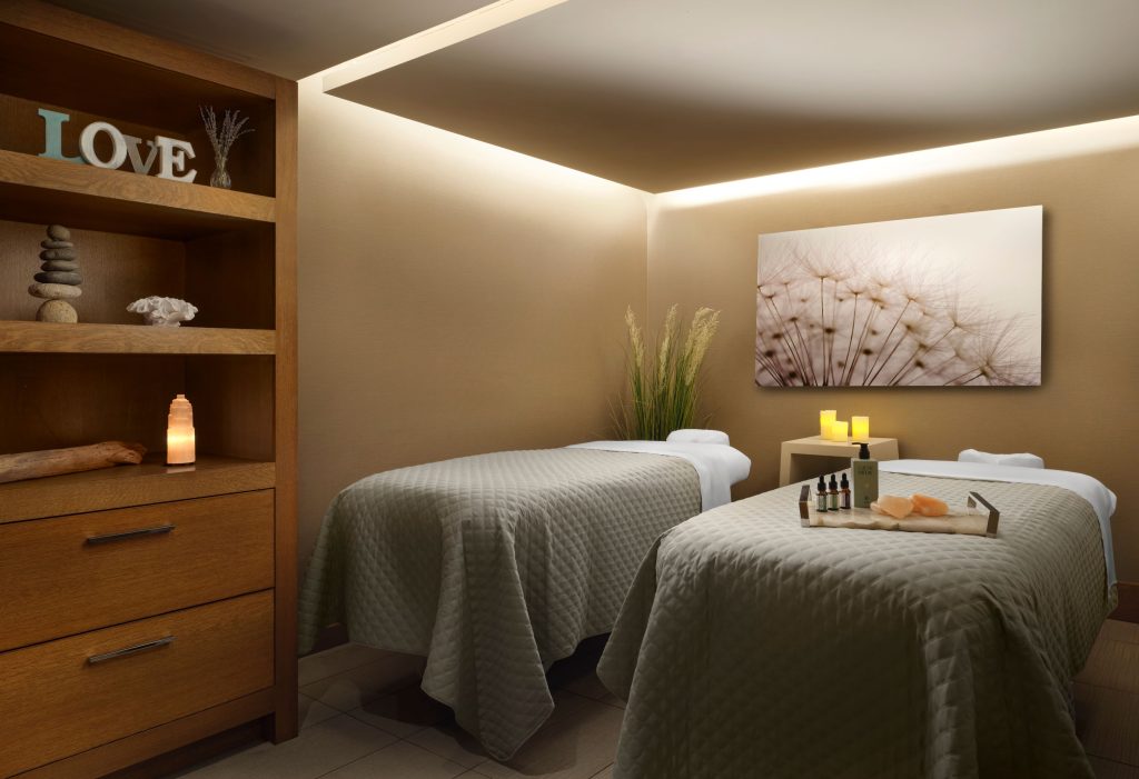 A serene spa treatment room with two massage tables and warm ambient lighting in Portland Maine.